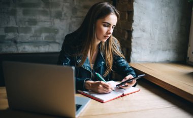 Modern cep telefonu cihazına sahip yetenekli bir kız öğrenci 4G internete, eğitim ders kitabı ve dizüstü bilgisayarına bağlanan ve araştırma için akıllı telefonu kullanan bir e-posta aldı.