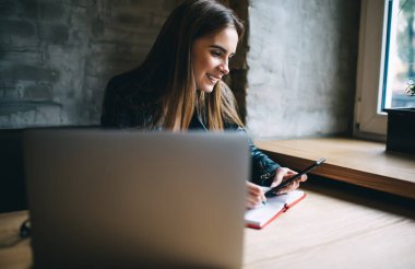 Modern cep telefonu zımbırtısına sahip mutlu kız öğrenci, araştırma için cep telefonunu kullanan, eğitim kitabı ve internet ile 4G internete bağlanan, neşeli bir e-posta aldı.