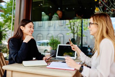 Gündüz vakti kafenin terasında proje tartışılırken elinde not defterleri ve siyah ekranlı dizüstü bilgisayarla masada oturan çok ırklı pozitif meslektaşlar