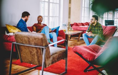 Gündelik giyinen farklı arkadaşlar birbirleriyle iletişim kurarak modern apartmandaki rahat mobilyalarda dinlenirler. Genç hippiler evlerinde boş vakitlerini birlikte geçirirler.