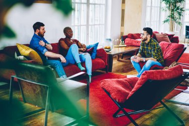 Erkek ve kadın meslektaşlar modern apartman dairesinde dostça bir toplantı sırasında moda tasarımı hakkında konuşuyor ve tartışıyorlar. Çeşitli hipster erkekler yurtta birlikte eğlenirken iletişim kuruyorlar.