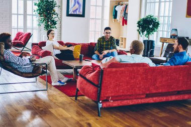 İyi görünümlü, gündelik kıyafetlerle gezen insanlar kahve içmek için gündüz vakitlerini harcayıp kırmızı mobilyalarla, genç erkeklerle ve kadınlarla birlikte evde rahatlamak hakkında konuşuyorlar.