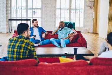 Çeşitli gençler kahve içip birbirleriyle iletişim kuruyorlar. Rahat bir dairede dostça bir toplantı yapıyorlar. Dinlenme haftasonu boyunca evde sosyalleşmek için çok kültürlü arkadaşlar konuşuyorlar.