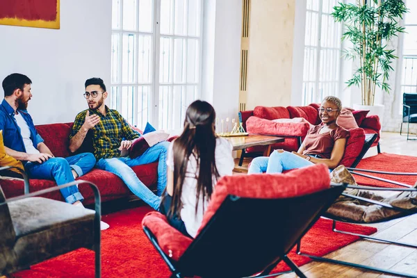 一群多种族的男女朋友在客厅里坐在红色的家具上交流 年轻的嬉皮士在舒适的室内聚会 讨论周末的计划 — 图库照片