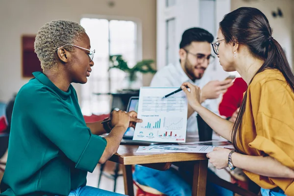 Donkere Huid Kaukasische Vrouwelijke Partners Analyseren Grafische Kaarten Tijdens Papierwerk — Stockfoto