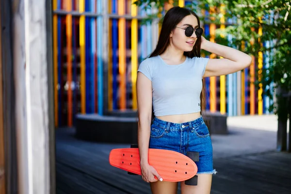 カジュアルな服を着たティーンスケーターでスタイリッシュなサングラスを持っているペニーボードと思慮深い離れてレジャー夏の週末の間に スケートボードと白人ヒップスターの女の子アドレナリンについて考える — ストック写真