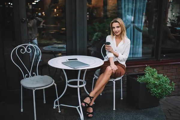 Full Length Alluring Woman Sitting Table Gadgets Crossed Legs Looking — Stock Photo, Image