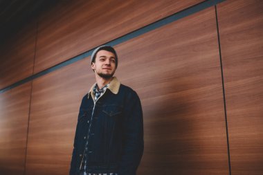 Sakin, sıradan giyimli, şapkalı bir erkeğin yürüme sırasında sokağın kenarındaki tahta duvara baktığı yerden.