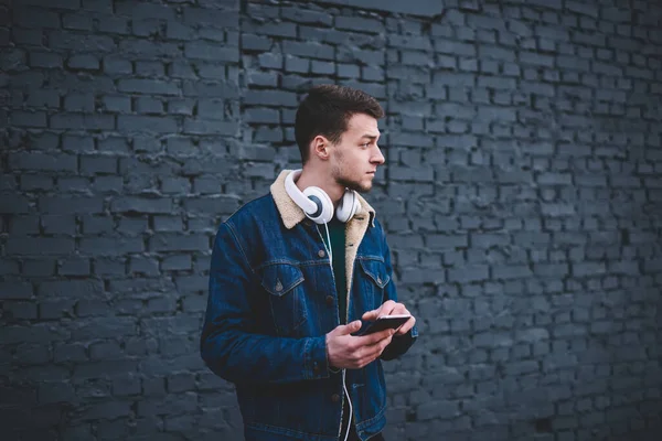 Pensive Guy Casual Wear Headphones Neck Browsing Smartphone Looking Away — Stock Photo, Image