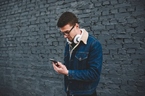 Vista Lateral Hombre Joven Chaqueta Mezclilla Con Auriculares Navegación Teléfono — Foto de Stock