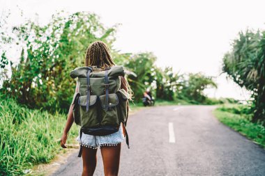 Sırt çantalı Afrikalı Amerikalı kadın turistin tropikal adada yaz macerası boyunca doğa koşullarını araştırması. Açık hava sırt çantalı koyu tenli aktif kadın.
