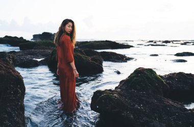 Bali tatil köyünde sakin bir denizde vakit geçirirken omzunun üzerinden kameraya bakan muhteşem bir kadın modelin tüm vücudu.