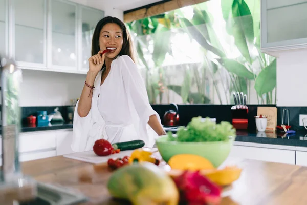 Mulher Asiática Encantadora Roupas Elegantes Comer Vegetais Enquanto Prepara Salada — Fotografia de Stock