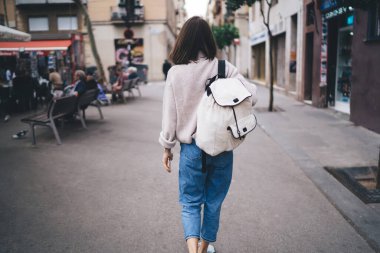 Sırt çantalı, sırt çantalı, yüzsüz, stil yoksunu turistin haftasonunu şehirde geçirmesi ve açık hava kafesinin yakınında yürümesi.