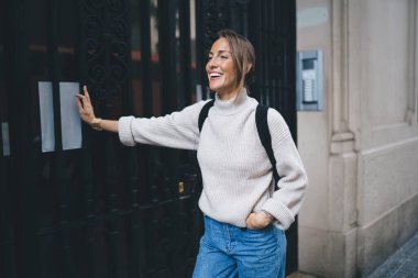 Sırt çantalı neşeli Kafkasyalı turist seyahatleri sırasında kendini tatmin olmuş hissediyor. Günlük giysiler içinde neşeli bir kadın. Şehir merkezine gülüyor ve tatillerde uluslararası yolculuğun tadını çıkarıyor.