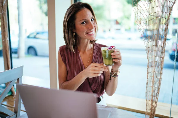 음료를 유리잔을 원격으로 작동하는 카메라를 코카서스 여성의 길이의 카페에서 컴퓨터를 — 스톡 사진