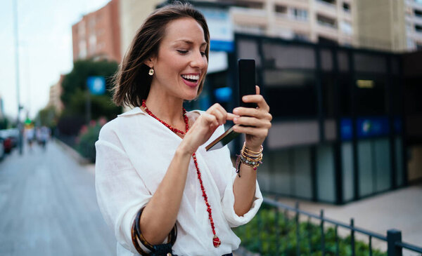 Веселая женщина туристка проверяет косметику маркер или порошок стоя в городской обстановке и с помощью палитры с зеркалом, счастливая женщина, глядя на отражение Попробуйте косметические средства и подготовиться к дате