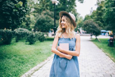 Kişisel günlüğü olan mutlu Kafkasyalı öğrenci, kamu parkında boş zamanlarında gülümsüyor ve avare kadın blogcu, modaya uygun şapka harcamalarının keyfini çıkarıyor.