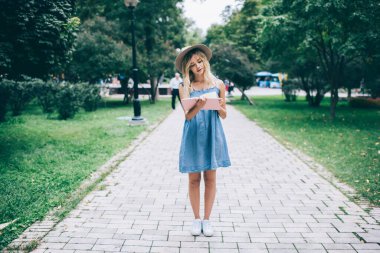 Moda kıyafetleri içinde çekici bir bayan öğrenci eğitim kitaplarındaki bilgileri kontrol ediyor, şık şapkalı genç bir hippi kız parkta dururken edebiyat dergisi okuyor.