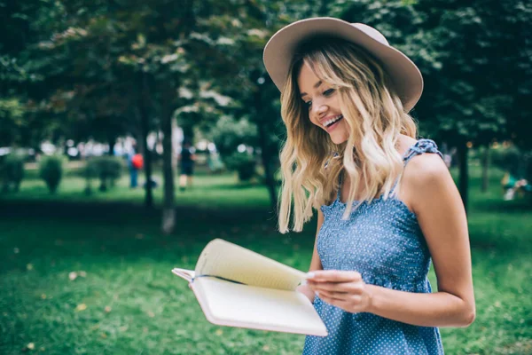 모자를 주말에는 공원에서 메모지로 출판물을 읽으면서 미소를 야외에서 여가를 즐기며 — 스톡 사진