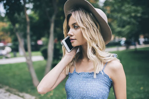 Beyaz tenli çekici bir bayan turist uluslararası gezici cep telefonu sohbeti yapıyor, modaya uygun şapkalı yeniyetme kız akıllı telefon teknolojisiyle hizmet ile iletişim kuruyor.