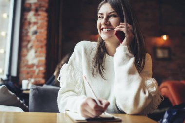 Mahsul, dişlek tebessümlü, uzaktan kumandalı, tahta masaya oturmuş, telefonda konuşan kadın çalışanı memnun etti.