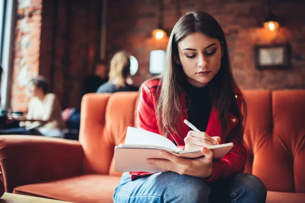 Estudiante Femenina Concentrada Ropa Casual Sentada Cafetería Ligera Escribiendo Notas — Foto de Stock