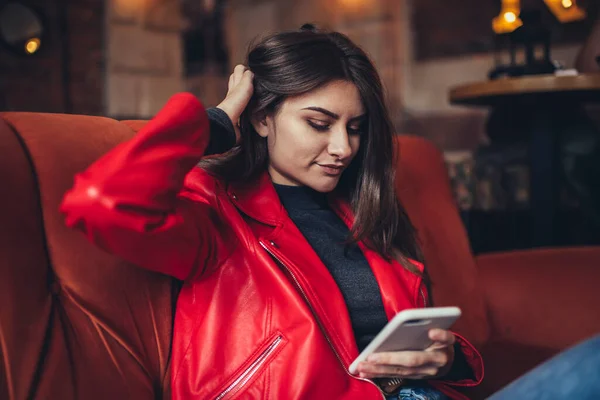 Pensive Female Vivid Jacket Sitting Sofa Touching Hair While Using — Stock Photo, Image