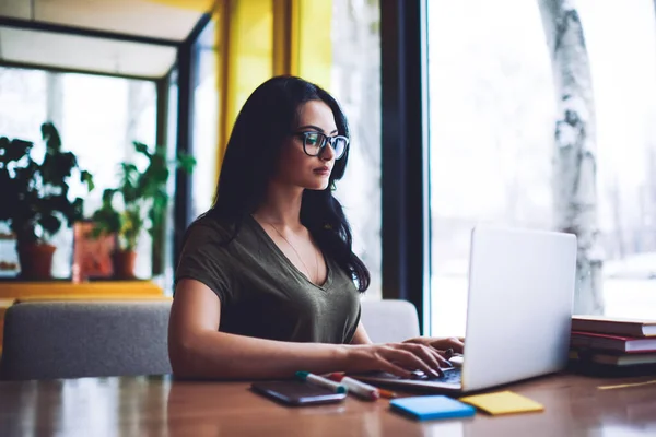 Konzentrierte Junge Unternehmerin Brille Sitzt Mit Smartphone Und Planer Tisch — Stockfoto