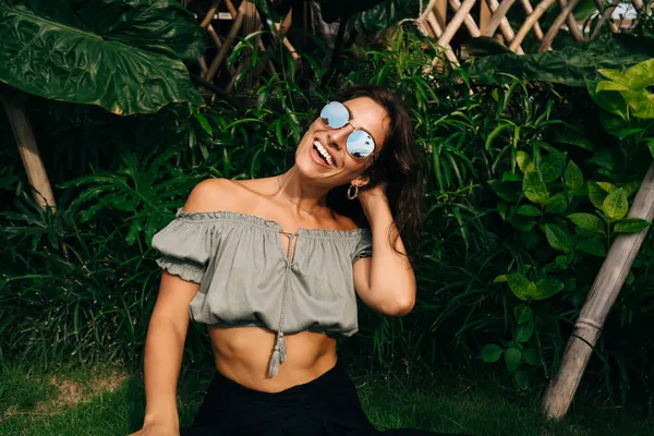 Счастливая Молодая Женщина Трикотажном Наряде Солнцезащитных Очках Касающаяся Волос Улыбающаяся — стоковое фото