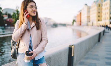 Esmer, bin yıllık kadın göz giysisi ve şık giysiler içinde açık havada cep telefonu sohbeti yapıyor. Kahvesini elinde tutuyor. Kafkasyalı turist cep telefonuyla interneti kullanıyor.