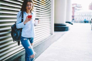 Optik göz giysisi okuyan beyaz kız öğrenciye akıllı telefondan kablosuz bağlantı kullanılarak mesaj geldi. Sırt çantası ve kahveli milenyum blogcusu sosyal medyaya postalanacak.