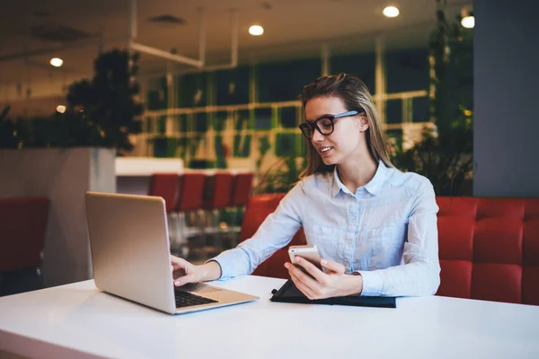 Fröhliche Studentin Brille Und Hellem Hemd Blättert Netbook Und Handy — Stockfoto