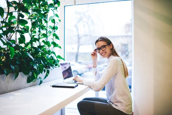 Vue Latérale Joyeux Freelance Féminin Tenue Décontractée Lunettes Regardant Caméra — Photo