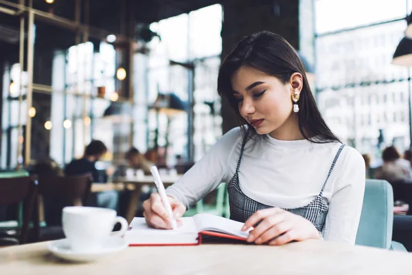 Schülerin Lässigem Outfit Sitzt Mit Tasse Kaffee Tisch Und Schreibt — Stockfoto