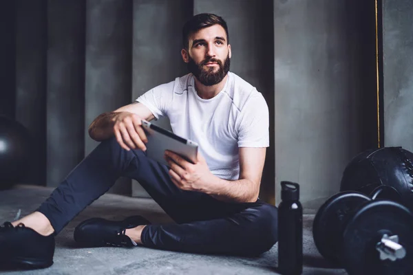 Young Bearded Man Sportswear Sitting Floor Using Tablet Resting While — Stock Photo, Image