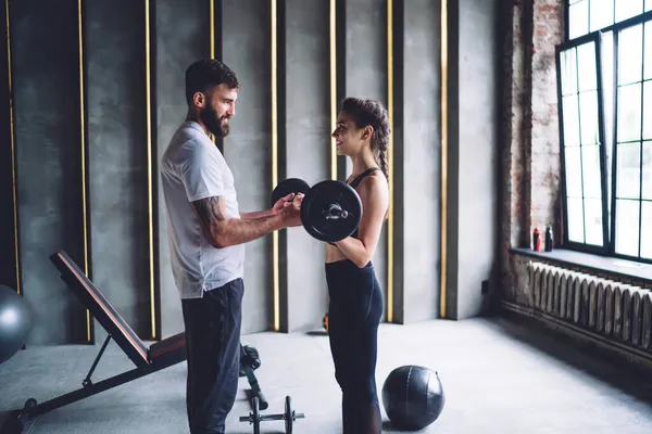 恋爱中的一对年轻夫妇在健身房里保持着完美的体形和健康的生活方式 职业男性健身教练帮助他的女性客户进行手臂肌肉锻炼 — 图库照片