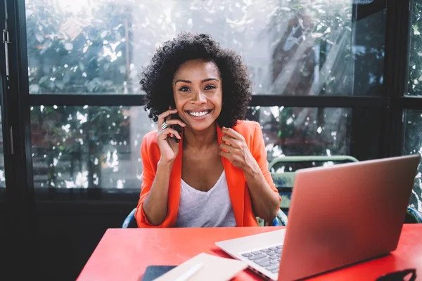 Positiv Ung Kvinna Med Bärbar Dator Ler Och Talar Smartphone — Stockfoto