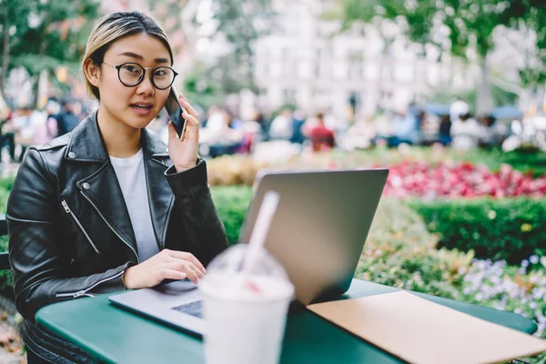Modern dizüstü bilgisayarda uzak mesafe işi yapmak için çekici Japon bilişim uzmanlarının portresi, arama ve konuşma için 4 G 'ye bağlanan gözlüklü yetenekli kadın.