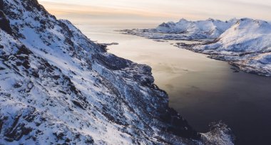Kışın karla kaplı fiyort dağlarının nefes kesici kuş bakışı görüntüsü. Hava manzaralı kaya zirveleri, resimli güzel doğa manzarası. Lofoten Adası İskandinav bölgesiyle çevrilidir