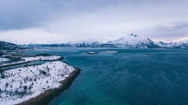 Kışın karla kaplı fiyort dağlarının nefes kesici kuş bakışı görüntüsü. Hava manzaralı kaya zirveleri, resimli güzel doğa manzarası. Lofoten Adası İskandinav Denizi ile çevrilidir