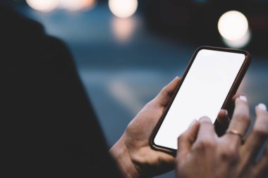 Parmak ucunda altın yüzüklü, cep telefonu kılıfında modern cep telefonlarını karıştıran tanınmamış bir kadın.