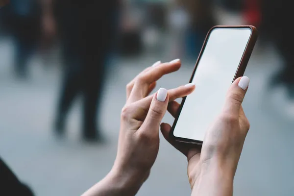 都会の通りで自由な時間を楽しみながら 現代の携帯電話の画面にスタイリッシュなマニキュアタイプで匿名の女性をクロップ — ストック写真