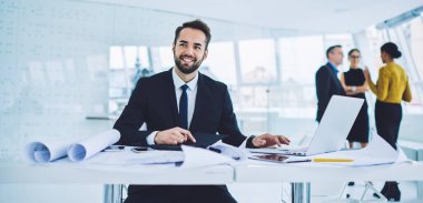 Başarılı resmi giyimli erkek girişimci başlangıç projesini geliştirmek için çalışma zamanının tadını çıkarıyor, mutlu iş adamı ofis içi masaüstünde oturan üretken stratejiyi analiz ediyor