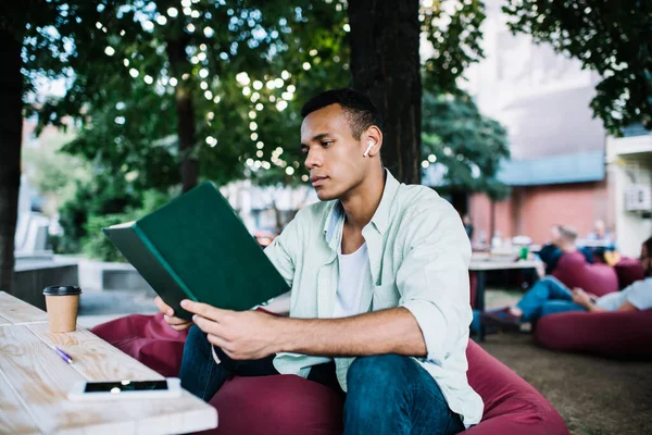 Estudante Negro Concentrado Com Fones Ouvido Tws Sentado Salão Beanbag — Fotografia de Stock