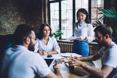 Masa başında doküman ve raporlarla konuşan akıllı erkek ve kadın girişimci planlar, öğrenim ve öğrenim için beyin fırtınası yapan bir grup öğrenci