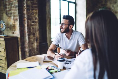 Göz giysisi içindeki neşeli Türk girişimci, dokunmatik defterden web sitesini tartıştığı için kadın meslektaşıyla vakit geçiriyor. Dijital tablet tutan mutlu erkek öğrenci toplantı sırasında başka tarafa bakıyor ve gülümsüyor.