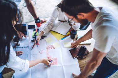 Modern ofisteki brifing sırasında proje üzerinde çalışan ve finansal raporları analiz eden isimsiz yaratıcı genç bir gruptan.