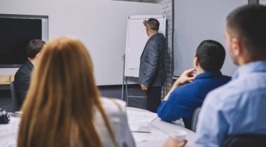 Yönetim kurulu brifinginde profesyonel çalışanlara koçluk yapan deneyimli patron 50 'li yaşlarda. Resmi takım elbiseli olgun bir şirket yöneticisi meslektaşlarına iş stratejisini açıklamaya çalışıyor.