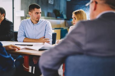 Resmi giyinmiş deneyimli çalışanlar, ofiste gerçekleşen beyin fırtınası sırasında iş planlarını tartışırken birbirleriyle iletişim kurarken, üretken planlamayı analiz eden erkek ve kadın uzmanlar